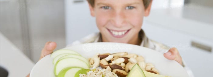 Подросток держит тарелку с фруктами и орехами