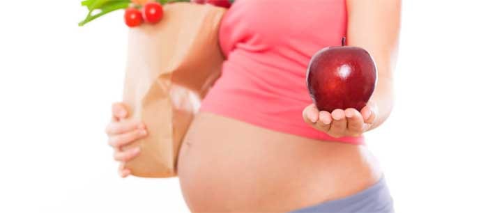 Беременная женщина с продуктами и яблоком
