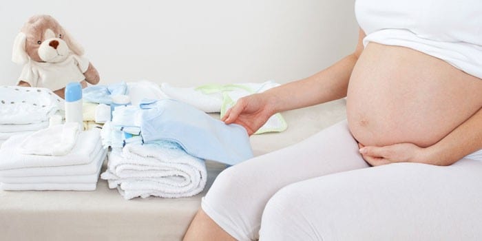 Беременная девушка и вещи для новорожденного