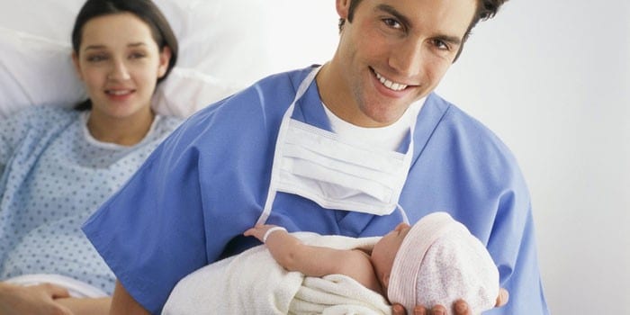 Роженица и врач с новорожденным ребенком на руках