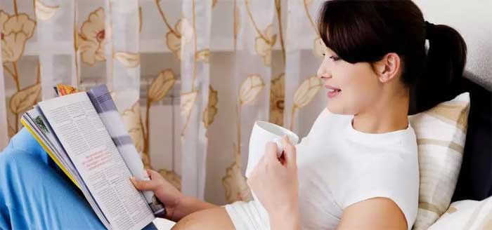 Беременная женщина читает журнал