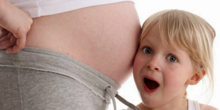 Девочка слушает живот беременной мамы