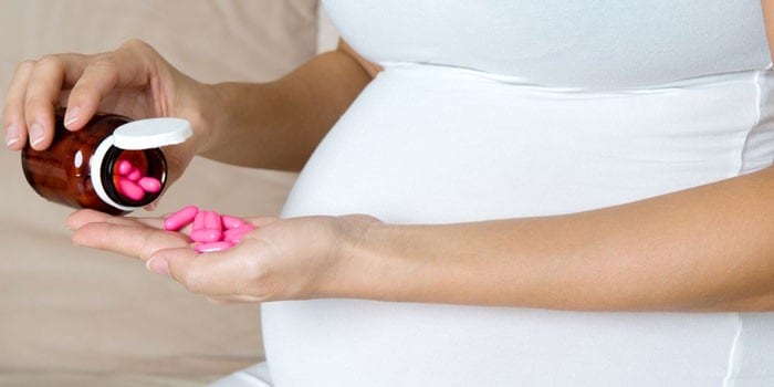 Беременная женщина с таблетками на ладони