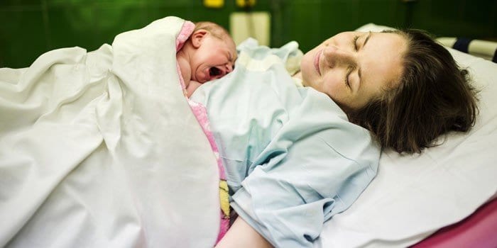 Женщина после родов с новорожденным ребенком