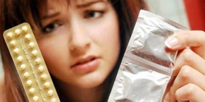 Девушка с противозачаточными таблетками и презервативами в руках