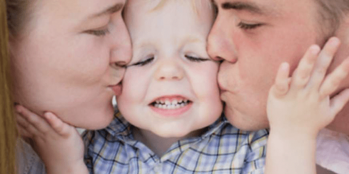 Родители целуют сына
