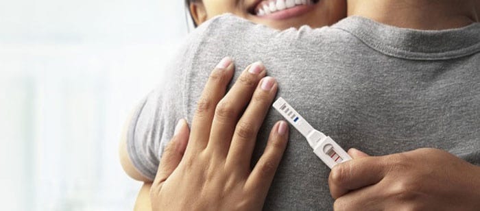 Мужчина и женщина обнимаются с тестом на беременность