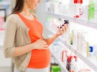 Беременная женщина выбирает витамины в аптеке
